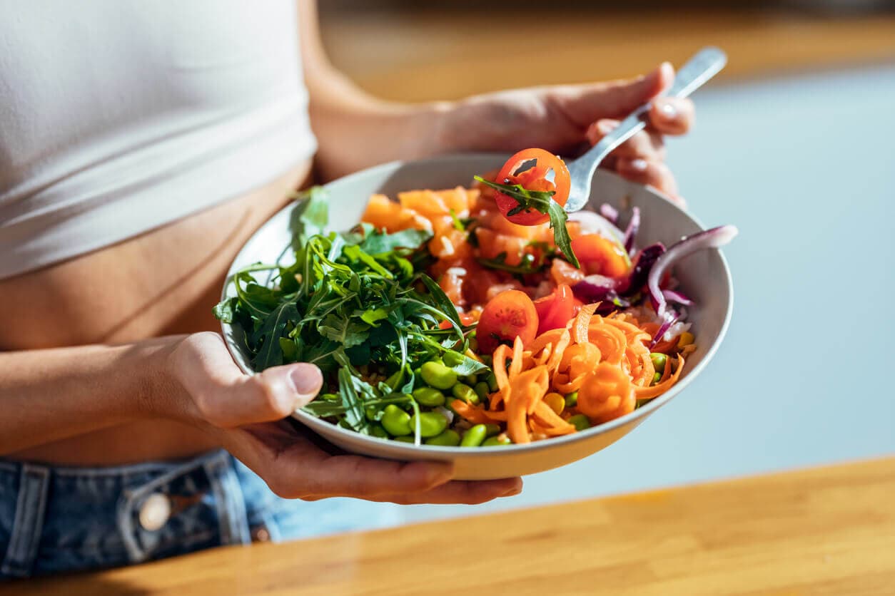 Mulher segurando um prato com verduras e legumes cozidos, exemplo de uma dieta ideal para alimentação no pós-operatório
